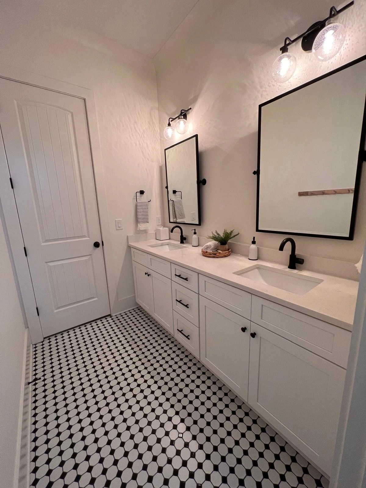Double vanity with black-framed mirrors and mosaic tile flooring — Weston, FL