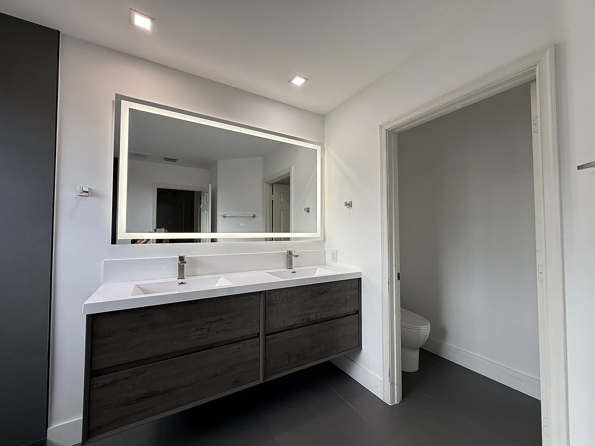 Wood double vanity with backlit mirror in a modern bathroom remodel