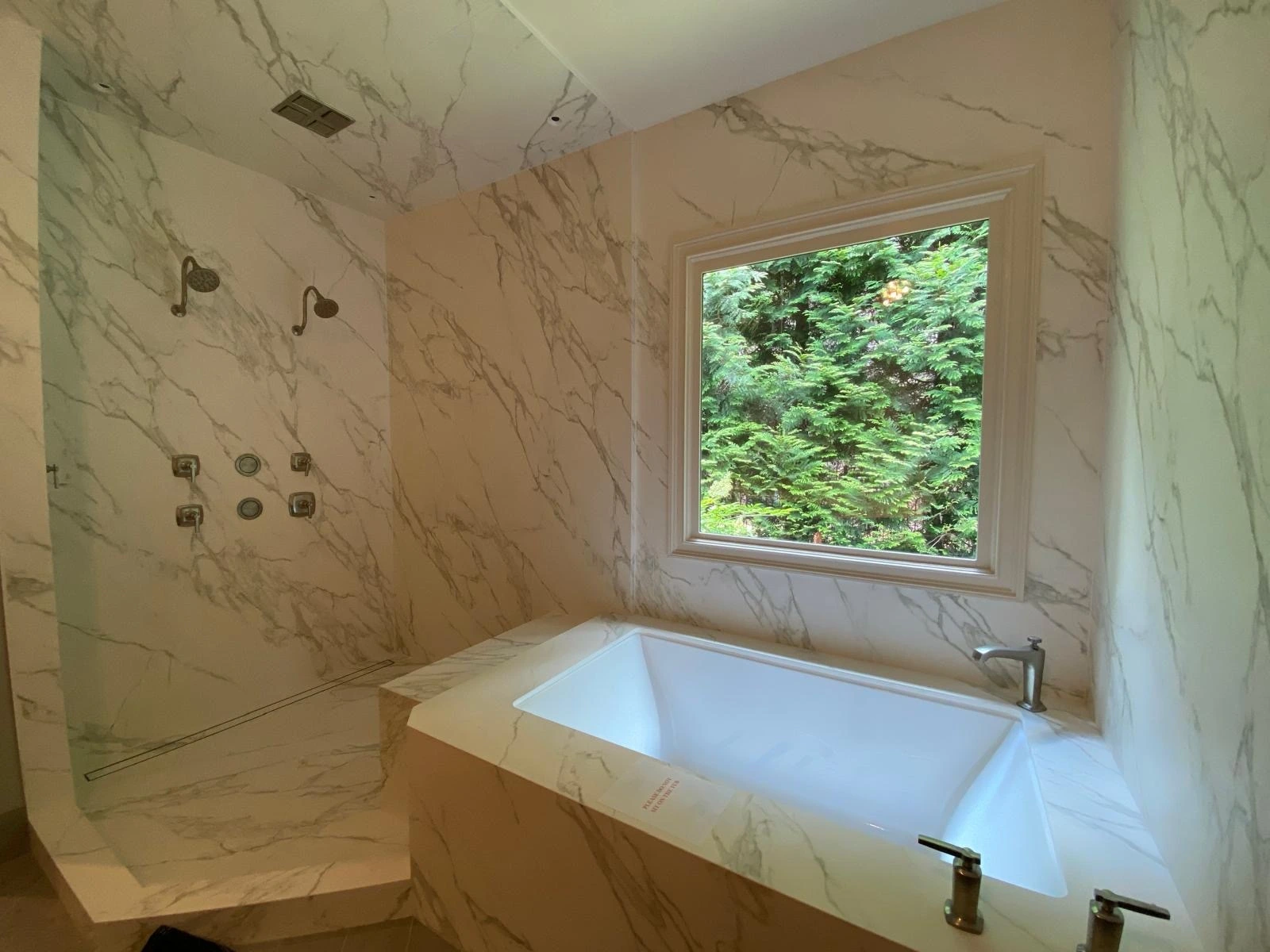 Drop-in soaking tub with full marble surround and picture window — Miami, FL