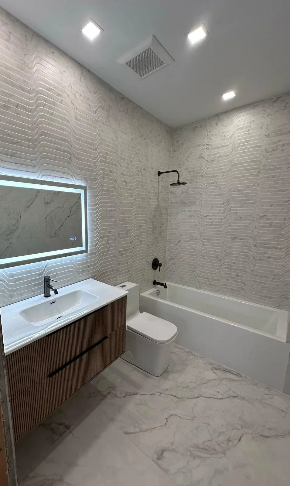 Renovated bathroom with glass shower enclosure and porcelain tile