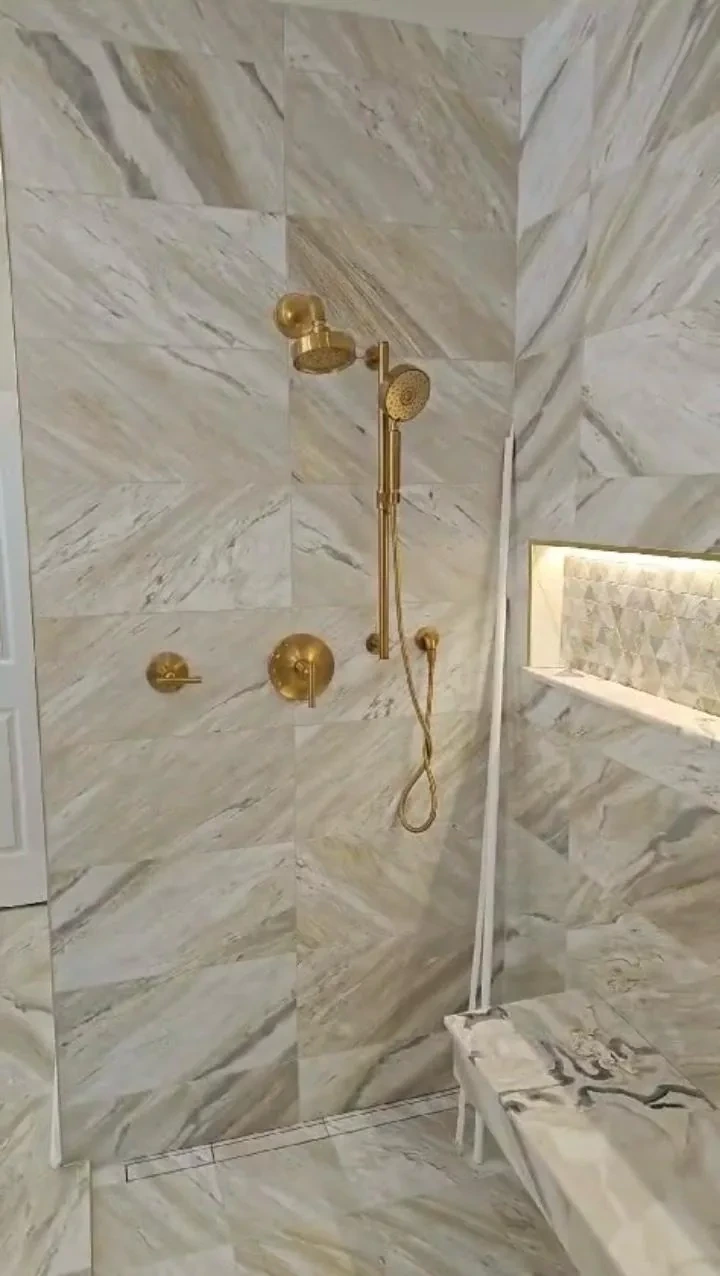 Walk-in shower with brushed gold fixtures and marble tile