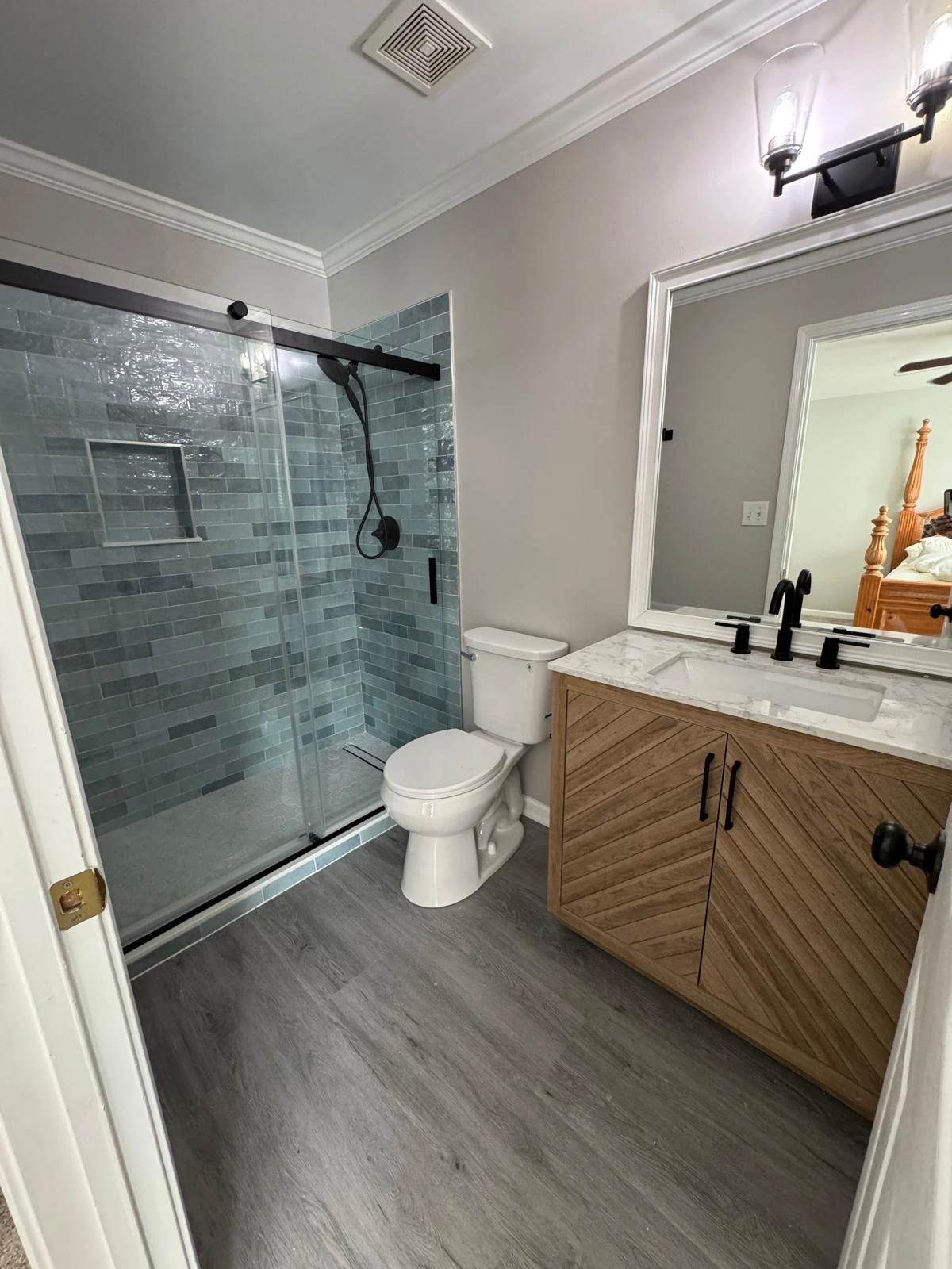 Sliding glass shower with grey tile and wood vanity
