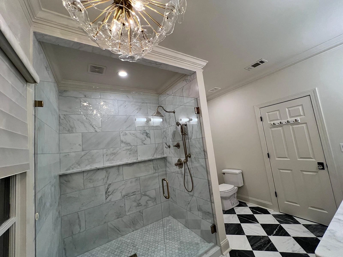 Marble shower enclosure lit by a crystal chandelier in a South Florida master bathroom