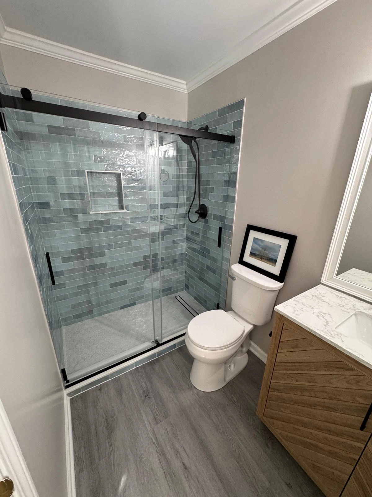 Sliding glass shower with teal tile and a wood floating vanity