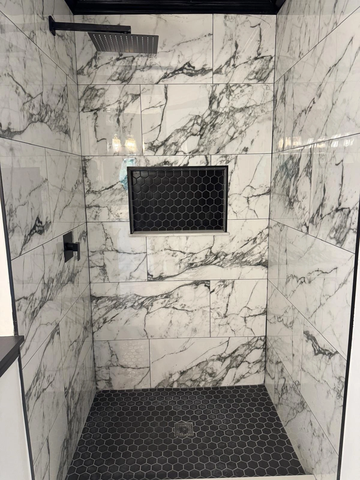 White marble shower with black hexagon pan and matte black fixtures