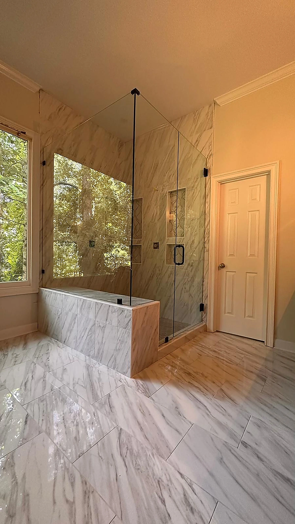 Marble bathroom with soaking tub and glass shower beside a window