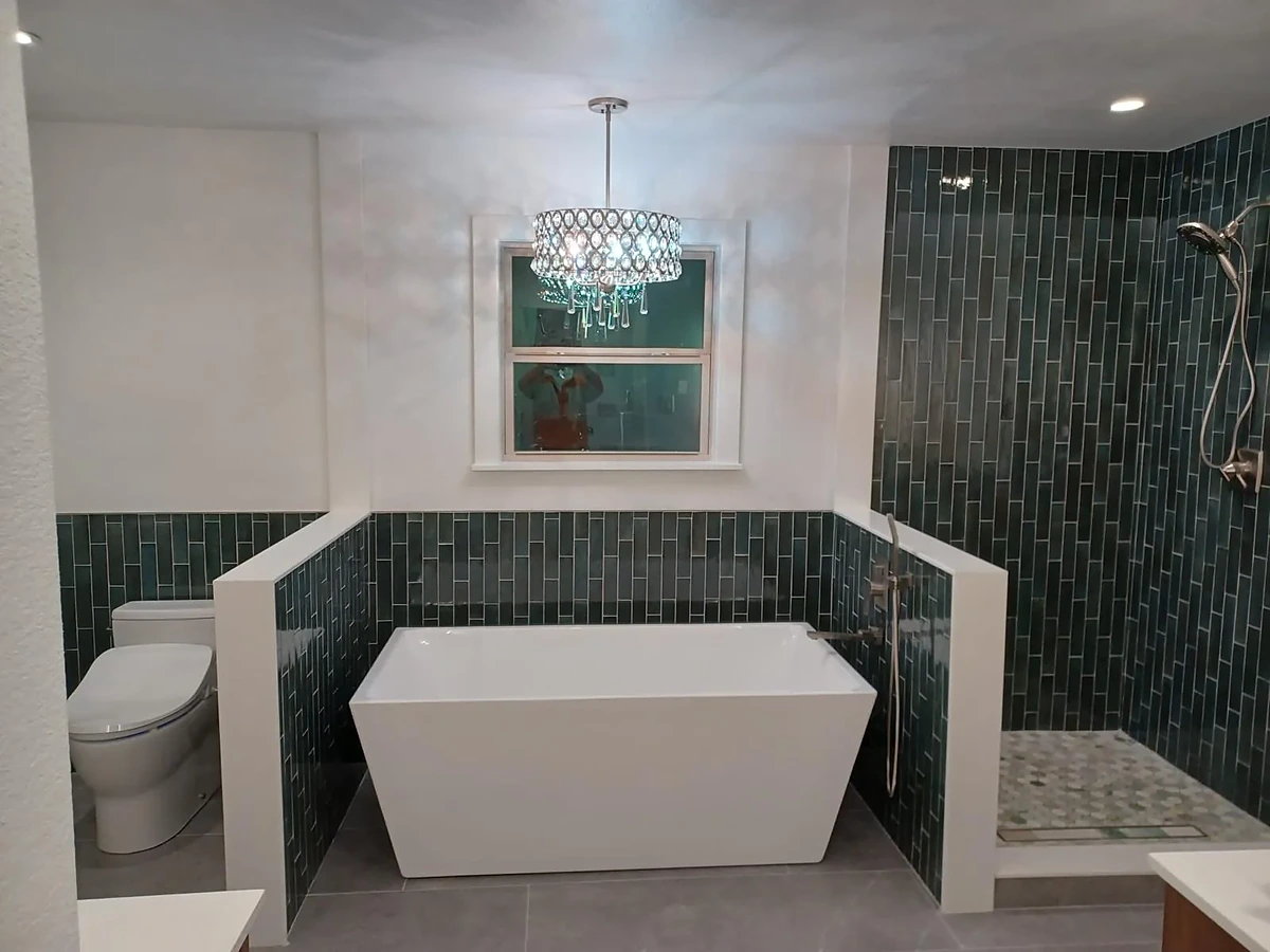 Bathroom with freestanding tub, green tile shower and crystal pendant light
