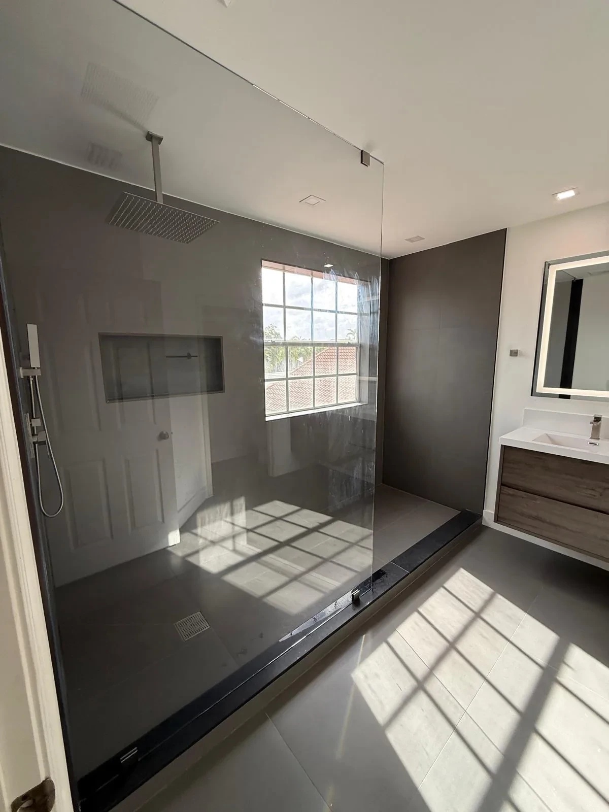 Wide bathroom with dark accent wall, glass shower and floating vanity
