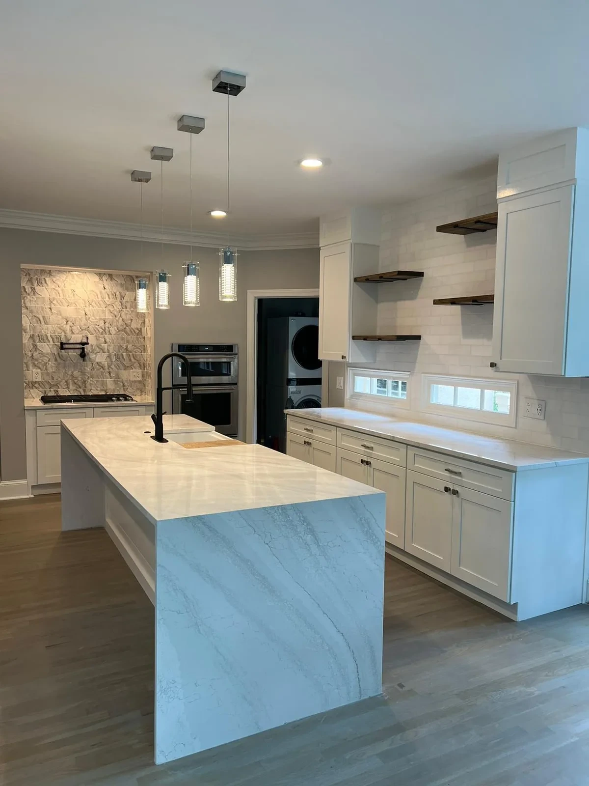 Kitchen island with quartz countertop, custom cabinetry and pendant lighting