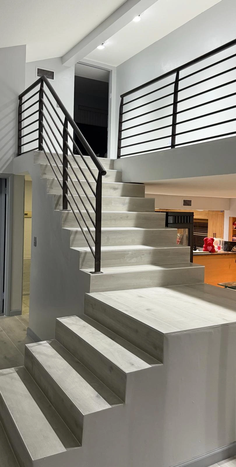 Grey wood-look porcelain plank tile flooring with matching staircase installation in South Florida home